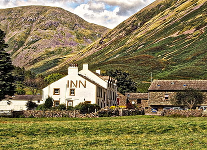 White Concrete Inn Near Green Covered Mountain at Daytime thumbnail