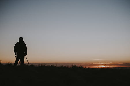 silhouette photo of person standing on grass field thumbnail
