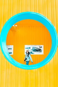 woman wearing blue jacket standing near yellow wall thumbnail