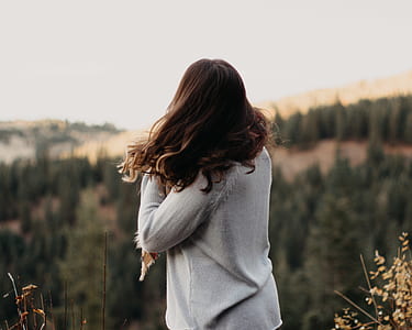 woman standing near cliff with trees in background selective focus photography thumbnail