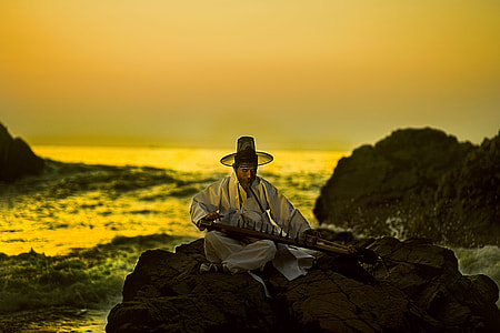 man playing string instrument on rock thumbnail