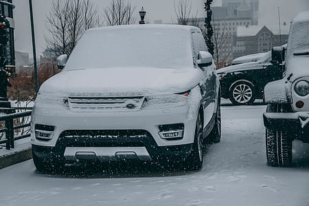 black and white Land Rover Range Rover parked beside gray Jeep Wrangler covered with snow thumbnail