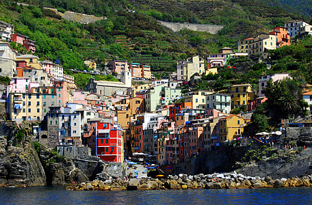 assorted-color concrete houses on the side of a mountain overlooking sea during day thumbnail