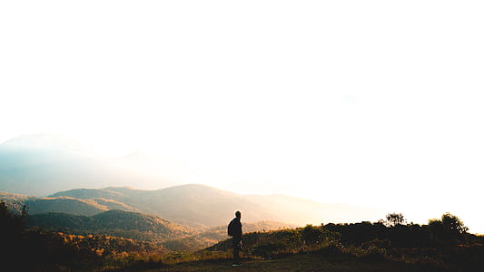 man standing on mountain under white sky thumbnail