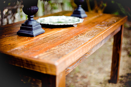 tilt shift lens photography of stainless steel plate between two black wooden decors on brown wooden table thumbnail