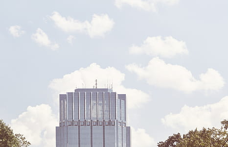 gray high-rise building near leafed trees under blue and cloudy sky at daytime thumbnail