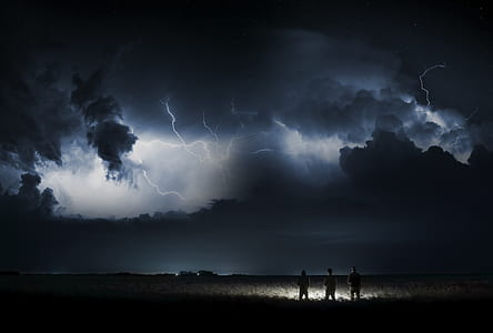 three men near grasses during nighttime thumbnail