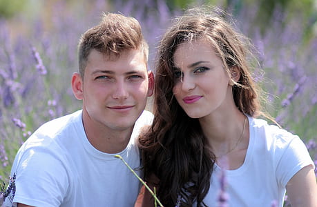 man and woman sitting next to each other surrounded by purple petaled flowers thumbnail