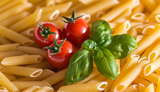three red tomatoes on raw pasta thumbnail