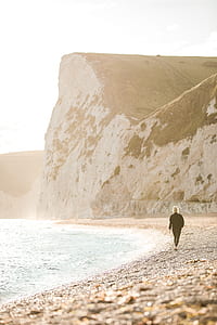 woman walking on seashore during daytime thumbnail