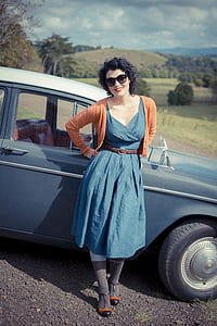 woman leaning on blue car outdoor during daytime thumbnail