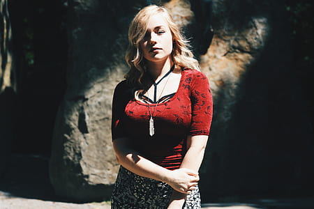 woman wearing red floral scoop-neck 3/4-sleeved shirt standing near gray and brown rock during daytime thumbnail