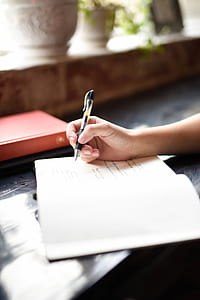 person holding ballpen while writing on paper thumbnail