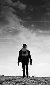 grayscale photography of man standing on grass field thumbnail