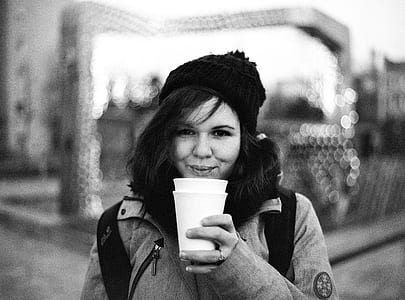 grayscale photography of woman blowing white cup thumbnail