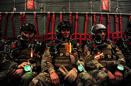 three men wearing helmet and air breathing equipment sitting down inside aircraft thumbnail