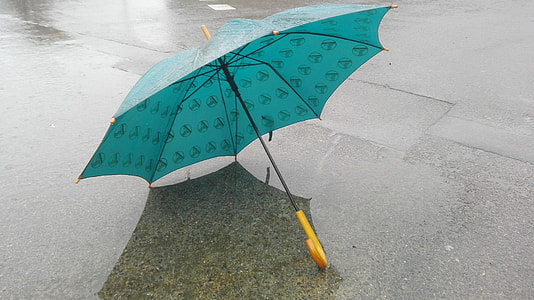 opened teal umbrella on gray pavement at daytime thumbnail