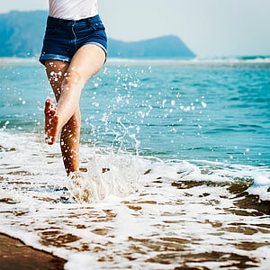 woman jumping on seashore beside waves thumbnail