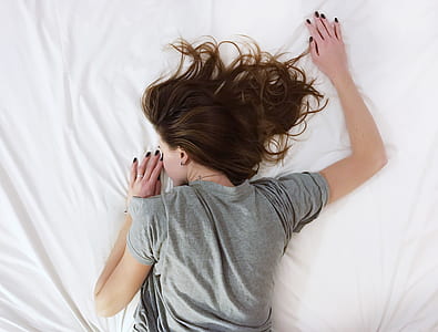 woman wearing gray t-shirt sleeping on white bed comforter thumbnail