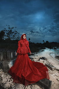 woman standing on gray concrete bar beside seashore under cloudy sky thumbnail
