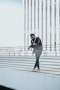 man resting his arms on metal rail of a building during day thumbnail