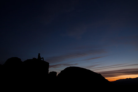 silhouette photography of person sitting on boulder thumbnail