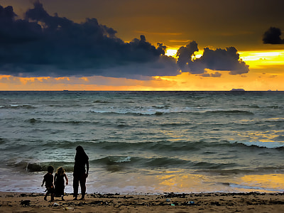 silhouette of woman and two toddlers on seashore thumbnail