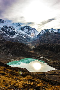 lake near mountain under cloudy sky at daytime thumbnail