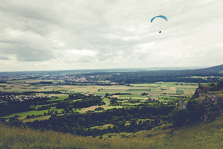 person paragliding over green grass field thumbnail