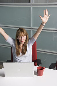 woman sitting near MacBook raising hands thumbnail