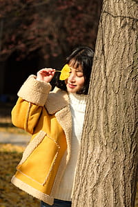 Woman Wearing Yellow Jacket Holding Yellow Leaf thumbnail