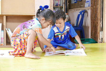 boy beside girl pointing book thumbnail