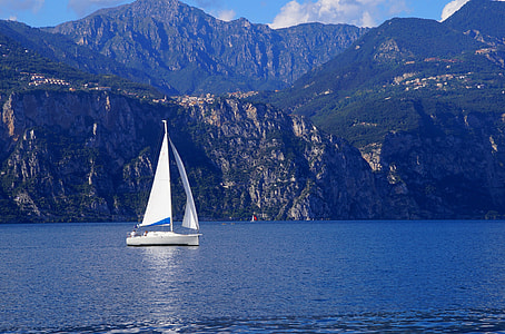 white sailing boat in sea near cliff thumbnail