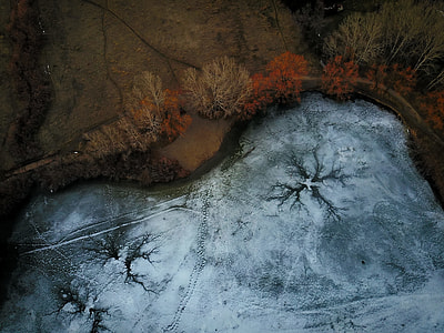 aerial view of frozen pond surrounded with trees thumbnail