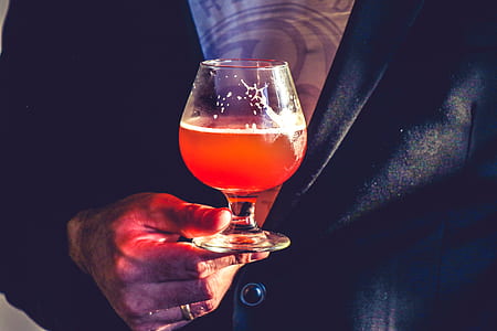 Person Holds Clear Glass Snifter With Red Beverage thumbnail