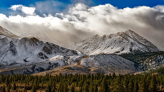 aerial photography of gray rock mountain covered with snow under blue sky and white clouds at daytime thumbnail