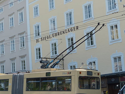 yellow bus beside H. Siegl. Uhrenlager building during daytime thumbnail