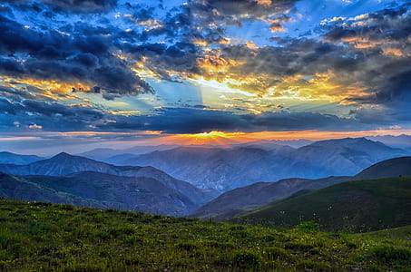 green grass field and blue mountains during sunset thumbnail