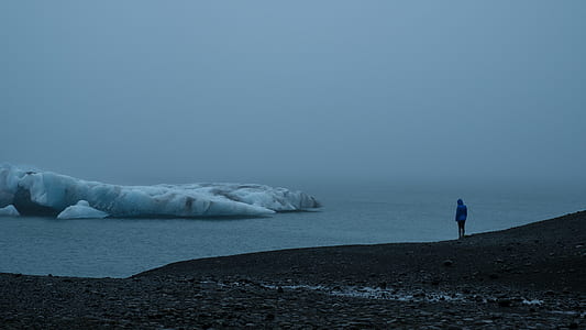 person standing on hill near sea and iceberg at daytime thumbnail