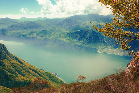photo of lake surrounded by mountains and trees under white sky during daytime thumbnail