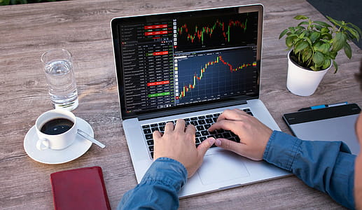 Photo illustration of person working at a laptop computer, which displays screen full of stock market data thumbnail