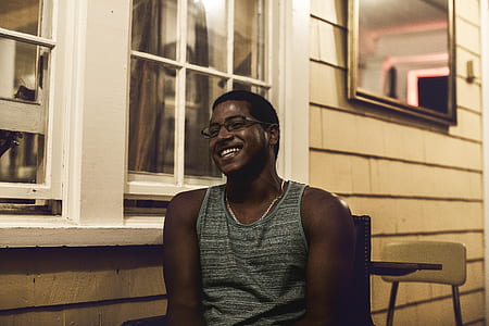 man smiling sitting near glass window thumbnail