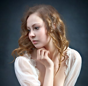 woman in white top pose for photo while hand on her neck thumbnail