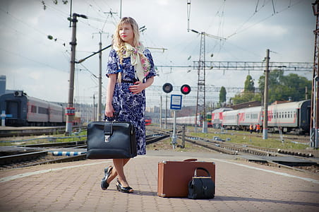 woman in blue and white floral elbow-sleeved dress holding black leather handbag during daytime thumbnail