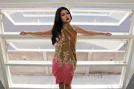 Standing Woman Wearing Brown and Pink Floral Dress Near Window thumbnail