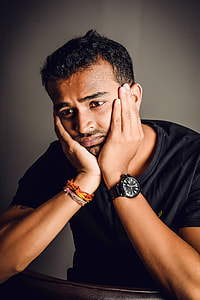 man wearing black crew-neck shirt sitting with hands on face thumbnail