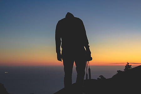 silhouette of person holding camera on top of hill thumbnail