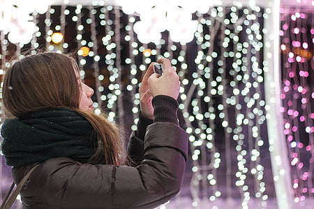 woman taking photo near string lights thumbnail