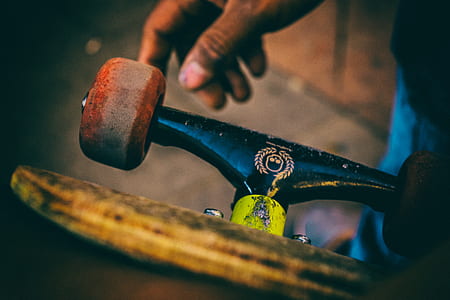 selective focus photography of person holding black and brown skateboard thumbnail