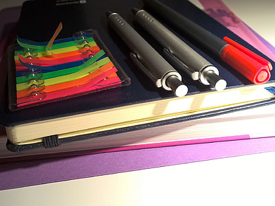 two gray retractable pens on top of blue book thumbnail